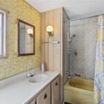 bathroom with wood paneling, yellow plaid wallpaper, and an ornate mirror