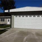 Real estate house with a large white garage door and a front lawn